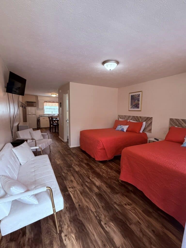 Motel room with two red beds and kitchenette